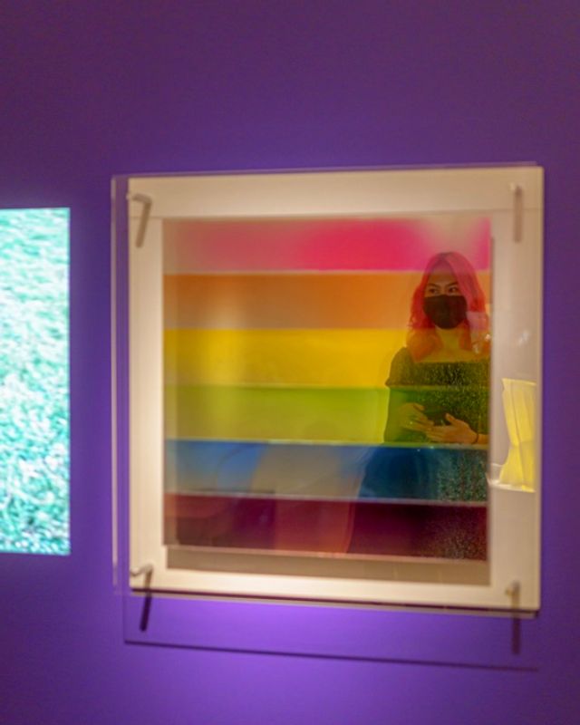 Girl taking a picture of her reflection in a rainbow mirror 