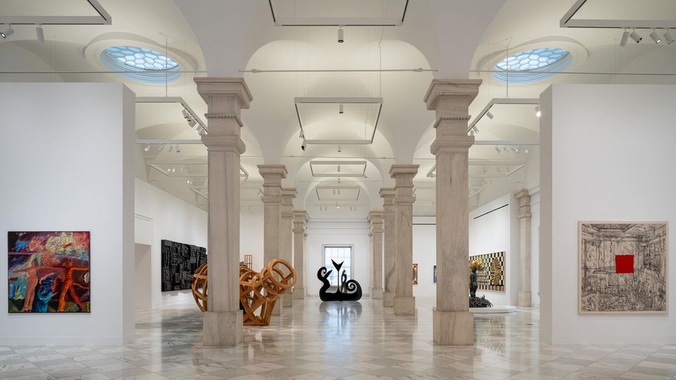 A light-filled gallery with marble columns and artwork