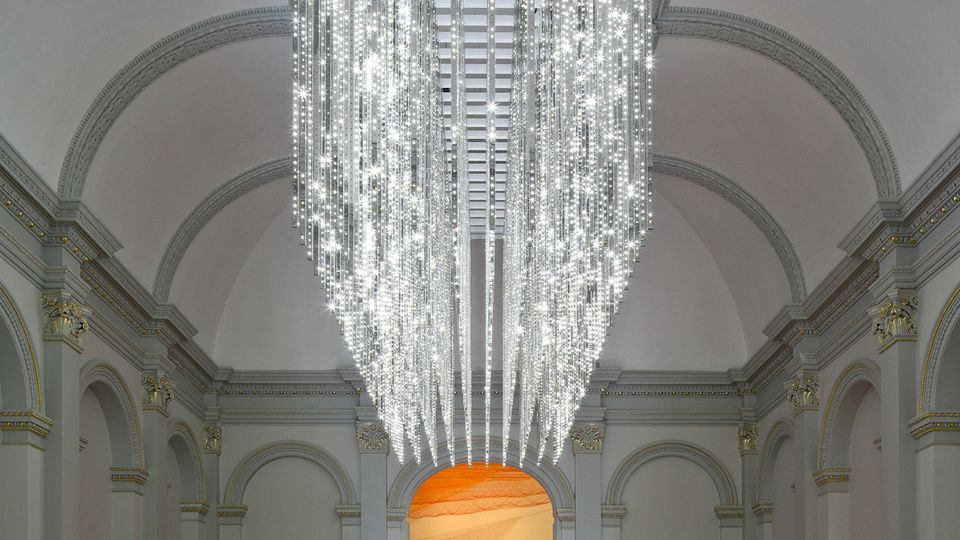 An angular and sparkling chandelier glimmers above a staircase