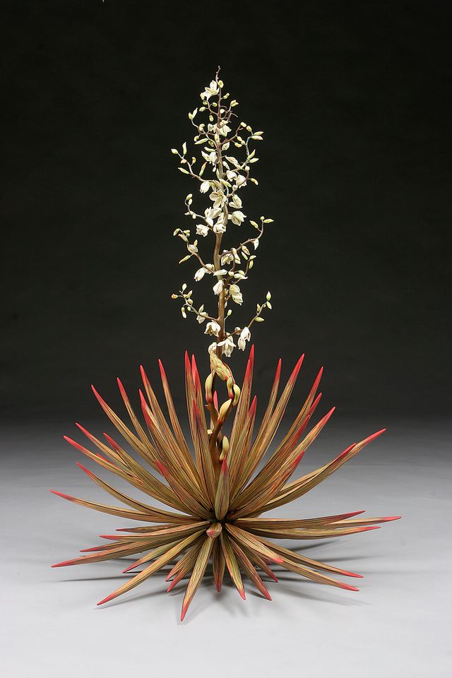 A ceramic plant with orange and red flowers at the bottom and a long stem with small white flowers.
